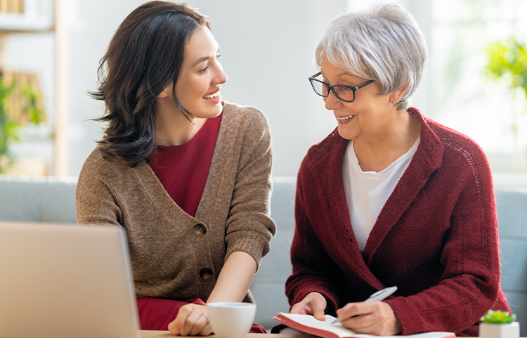 Une mère âgée et sa fille consultent leurs finances sur un ordinateur portable.